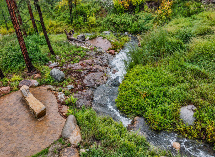 Discover a serene retreat with this charming outdoor seating area, perfectly situated beside a babbling brook.