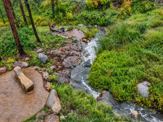 Discover a serene retreat with this charming outdoor seating area, perfectly situated beside a babbling brook.
