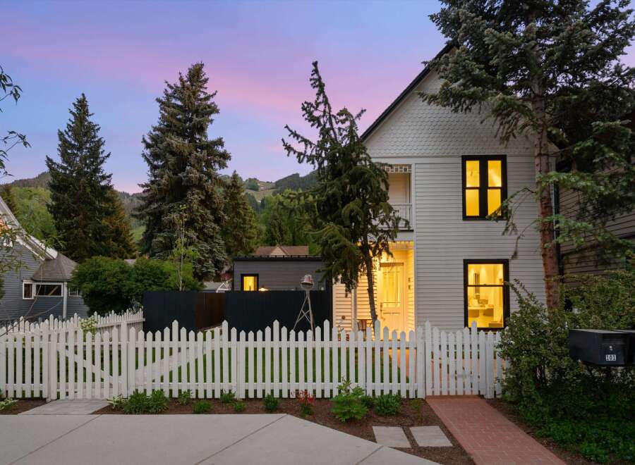 Charming home with a white picket fence and a welcoming brick pathway leading to the entrance.