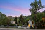 Charming homes nestled against a backdrop of lush green mountains under a vibrant twilight sky.