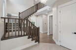 Step into this stunning foyer featuring a grand staircase with dark wood railings and carpeted treads, perfect for a luxurious home.