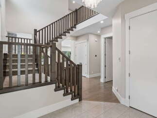 Step into this stunning foyer featuring a grand staircase with dark wood railings and carpeted treads, perfect for a luxurious home.