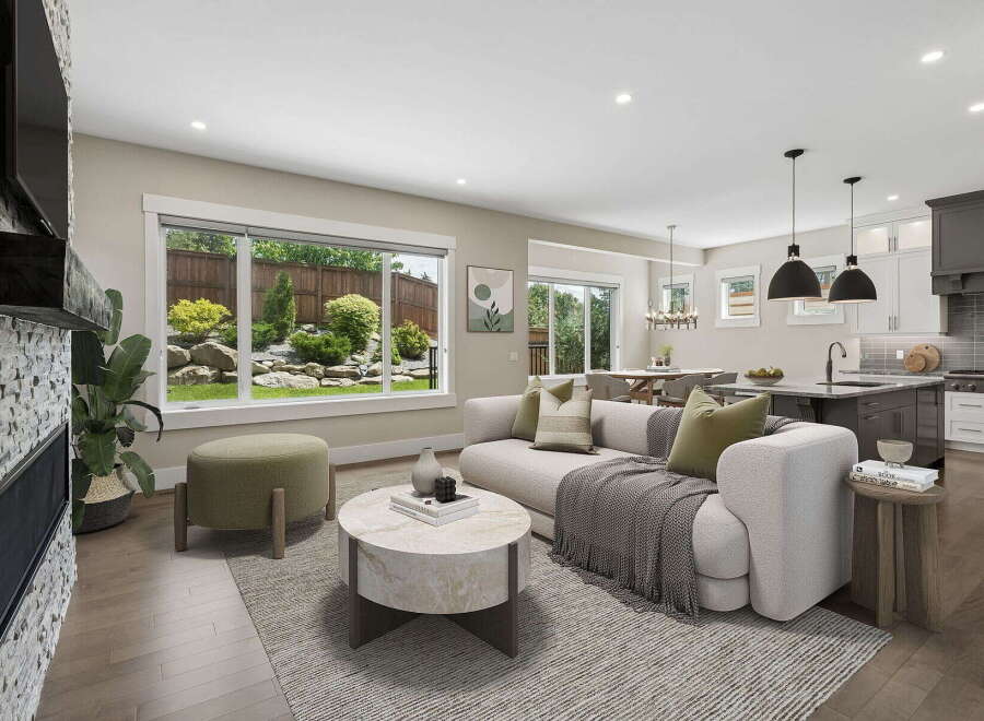 Experience modern living in this open-concept home featuring a spacious living area with a stone fireplace and large windows overlooking a lush backyard.