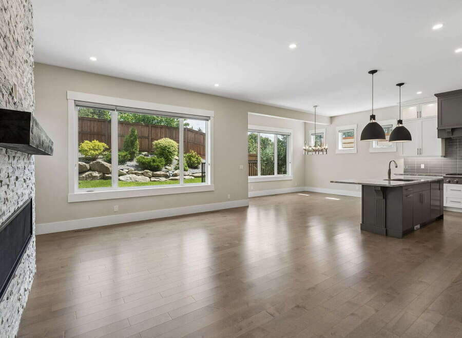 Experience modern living in this open-concept home featuring a stunning stone fireplace and expansive windows that flood the space with natural light.