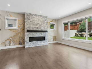 Experience modern living in this stunning living room featuring a striking stone fireplace and a unique marble-inspired accent wall.