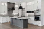 Experience luxury in this stunning modern kitchen, featuring sleek white cabinetry and a sophisticated gray island.
