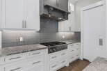Experience culinary excellence in this modern kitchen, featuring a professional-grade gas range and a sleek grey subway tile backsplash.