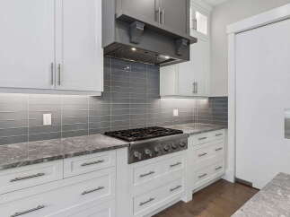 Experience culinary excellence in this modern kitchen, featuring a professional-grade gas range and a sleek grey subway tile backsplash.
