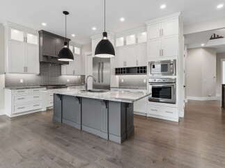 Experience luxury in this stunning modern kitchen, featuring sleek white cabinetry, a sophisticated grey island with a marble countertop, and high-end stainless steel appliances.