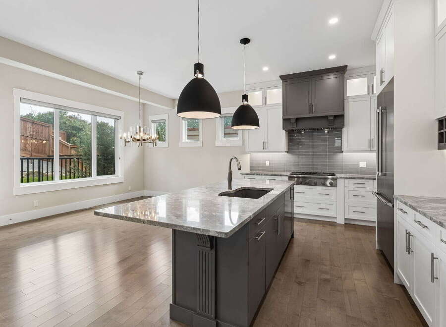 Experience luxury in this modern kitchen featuring a spacious island with a waterfall countertop and a deep sink.