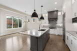 Experience luxury in this modern kitchen featuring a spacious island with a waterfall countertop and a deep sink.
