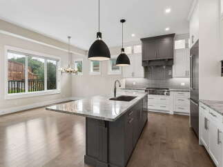 Experience luxury in this modern kitchen featuring a spacious island with a waterfall countertop and a deep sink.