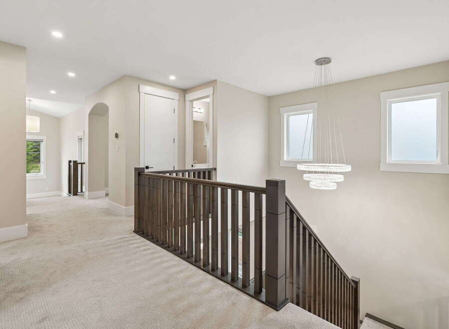 Experience modern elegance in this spacious hallway featuring plush carpeting and a stunning multi-tiered chandelier.