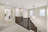 Experience modern elegance in this spacious hallway featuring plush carpeting and a stunning multi-tiered chandelier.