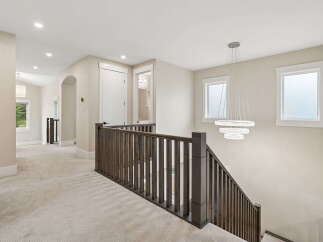 Experience modern elegance in this spacious hallway featuring plush carpeting and a stunning multi-tiered chandelier.