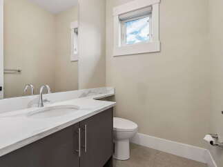 This modern bathroom features a sleek vanity with a quartz countertop and a undermount sink, complemented by chrome fixtures.
