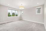 This spacious bedroom features a large picture window offering scenic views of trees and city skyline.