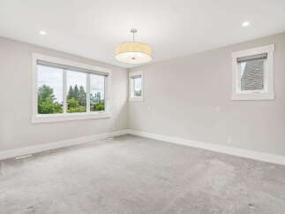 This spacious bedroom features a large picture window offering scenic views of trees and city skyline.