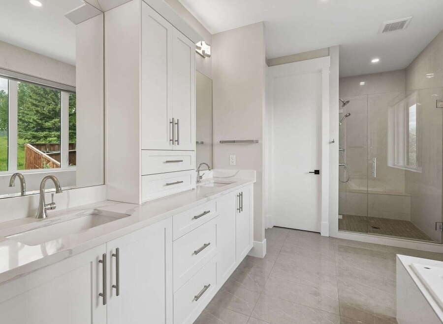 Experience luxury in this modern bathroom featuring a spacious double vanity with sleek cabinetry and quartz countertops.