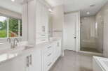 Experience luxury in this modern bathroom featuring a spacious double vanity with sleek cabinetry and quartz countertops.