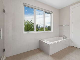 Experience luxury in this modern bathroom featuring a spacious soaking tub with a stunning city view.