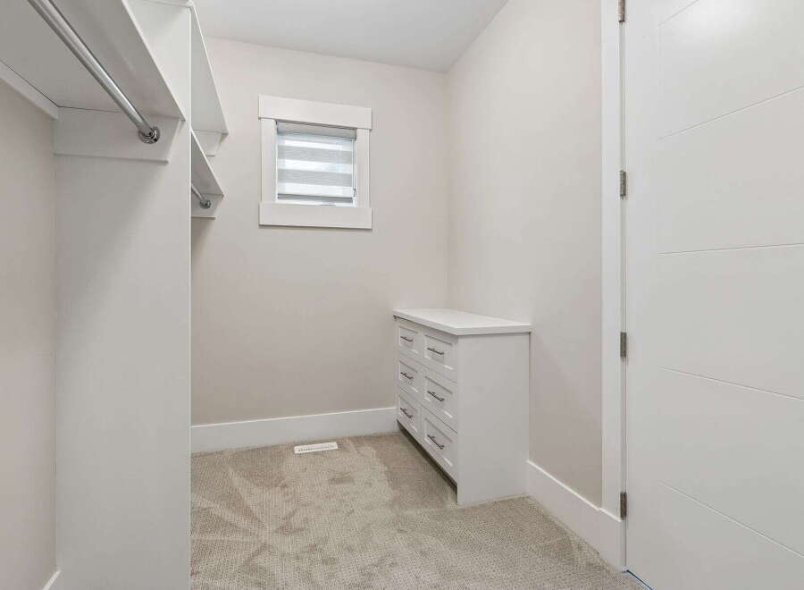 Step into this spacious walk-in closet, featuring ample hanging space and a built-in dresser for organized storage.