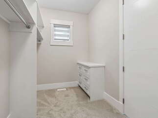 Step into this spacious walk-in closet, featuring ample hanging space and a built-in dresser for organized storage.
