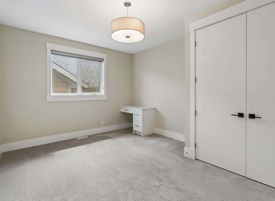 This bright and airy bedroom features a modern white desk with ample drawer space, perfect for a home office or study area.