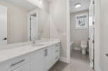 This modern bathroom features a sleek white vanity with a quartz countertop and undermount sink, complemented by a large vanity mirror.