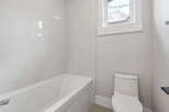 This modern bathroom features a sleek white bathtub with marble-patterned tile walls, creating a spa-like ambiance.