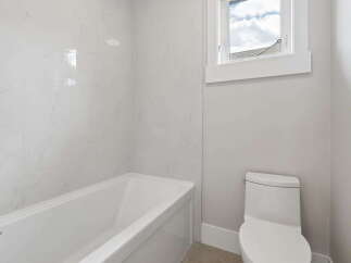 This modern bathroom features a sleek white bathtub with marble-patterned tile walls, creating a spa-like ambiance.