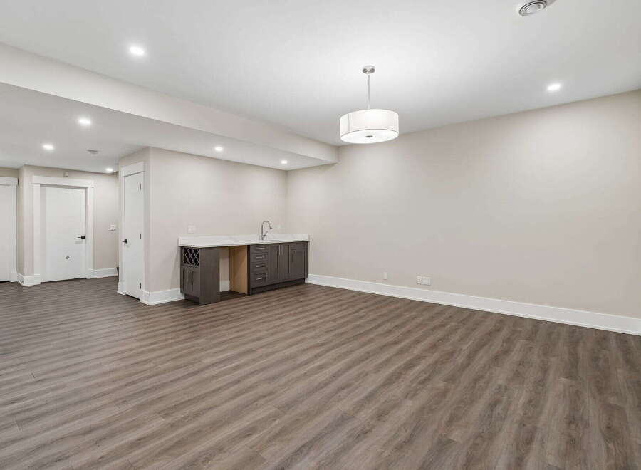 Discover this spacious basement featuring a modern wet bar with ample cabinet space and a wine rack, perfect for entertaining.