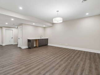 Discover this spacious basement featuring a modern wet bar with ample cabinet space and a wine rack, perfect for entertaining.