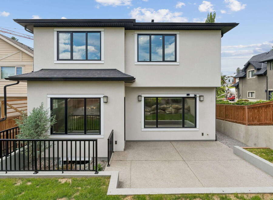 Discover modern living in this stunning home featuring a sleek stucco exterior and large, black-framed windows that flood the interior with natural light.