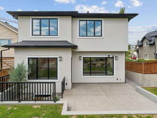Discover modern living in this stunning home featuring a sleek stucco exterior and large, black-framed windows that flood the interior with natural light.