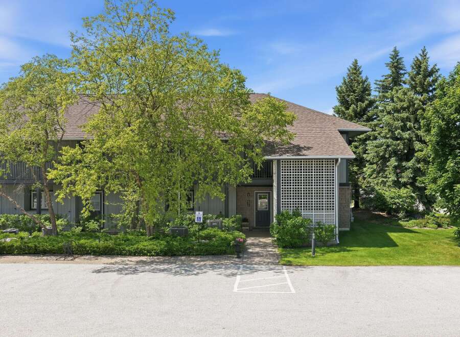 Discover this charming property featuring a welcoming entrance with a decorative lattice screen and a paved walkway leading to the front door.