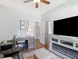 This inviting living space features a modern entertainment center with a large flat-screen TV and a sleek soundbar, complemented by a cozy electric fireplace.