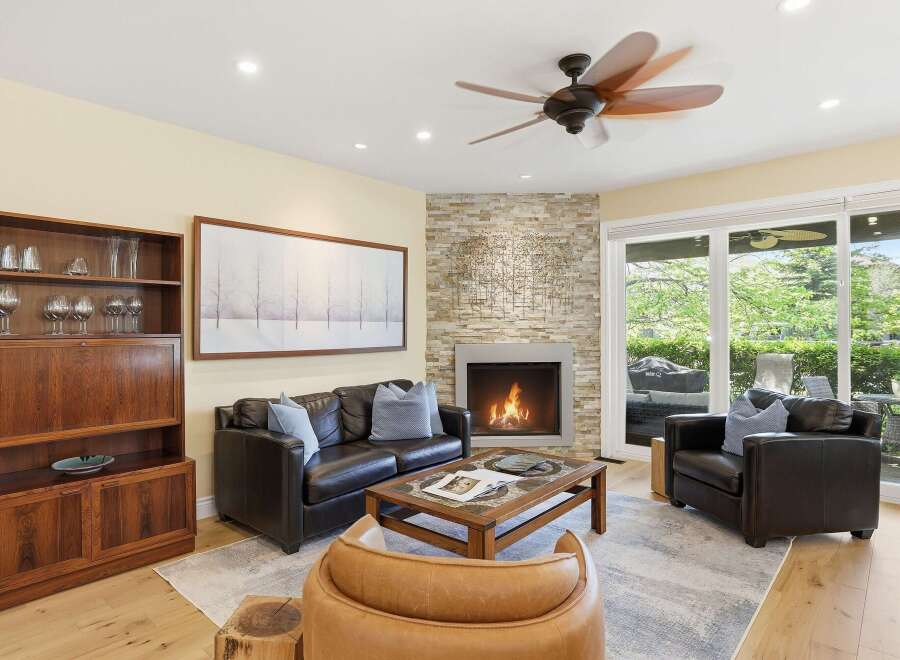 Experience ultimate comfort in this inviting living room, featuring a cozy fireplace with a stacked stone accent wall and a large picture window offering serene views.