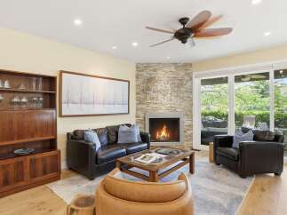 Experience ultimate comfort in this inviting living room, featuring a cozy fireplace with a stacked stone accent wall and a large picture window offering serene views.