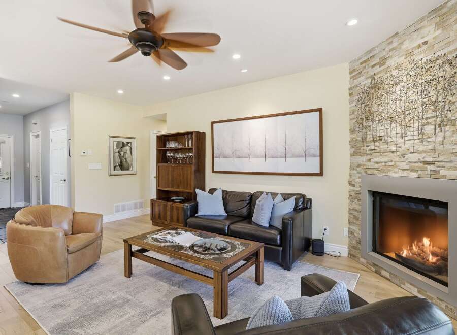 Experience modern living in this stunning living room, featuring a cozy fireplace with a stacked stone accent wall and a large, contemporary artwork.