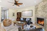 Experience modern living in this stunning living room, featuring a cozy fireplace with a stacked stone accent wall and a large, contemporary artwork.