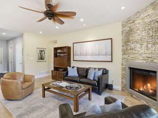 Experience modern living in this stunning living room, featuring a cozy fireplace with a stacked stone accent wall and a large, contemporary artwork.