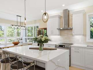Experience modern luxury in this stunning kitchen, featuring a spacious island with a quartz countertop and elegant pendant lighting.
