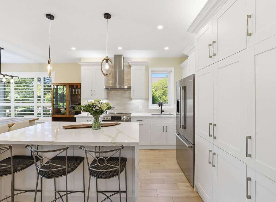 Experience luxury in this stunning modern kitchen, featuring a spacious island with a quartz countertop and comfortable bar stools.