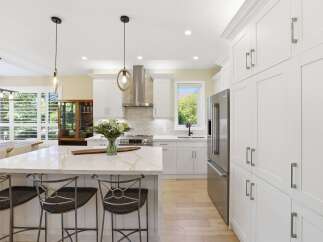 Experience luxury in this stunning modern kitchen, featuring a spacious island with a quartz countertop and comfortable bar stools.