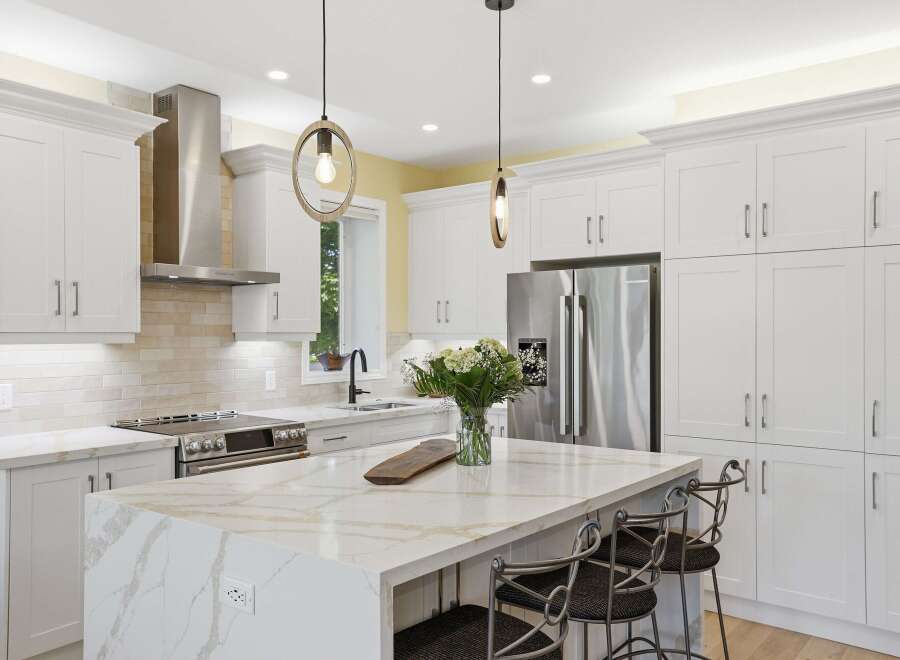 Experience luxury in this stunning modern kitchen, featuring sleek white shaker cabinets and a breathtaking quartz island with intricate veining.