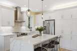 Experience luxury in this stunning modern kitchen, featuring sleek white shaker cabinets and a breathtaking quartz island with intricate veining.