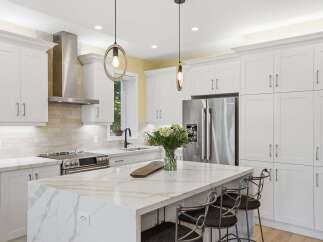 Experience luxury in this stunning modern kitchen, featuring sleek white shaker cabinets and a breathtaking quartz island with intricate veining.