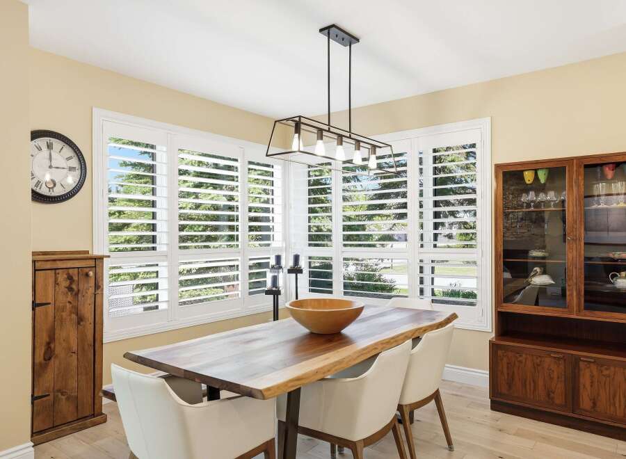 This dining room features a live-edge wood dining table with modern white chairs, illuminated by a stylish geometric chandelier.