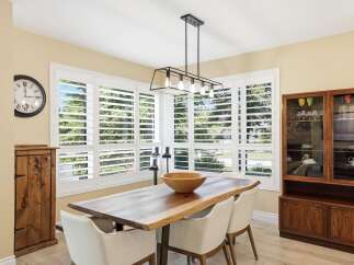 This dining room features a live-edge wood dining table with modern white chairs, illuminated by a stylish geometric chandelier.